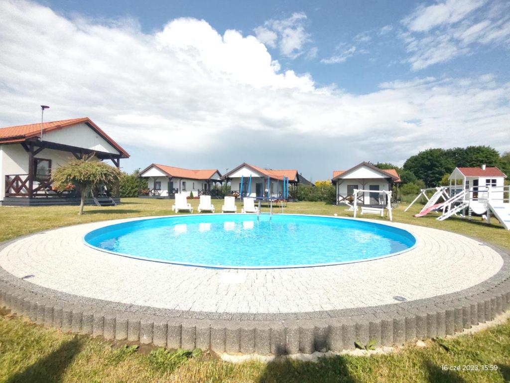 a large swimming pool in a yard with houses at Polne Domki in Darłowo
