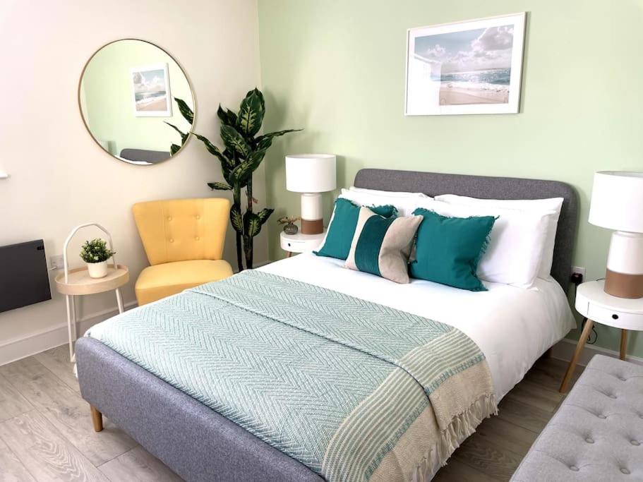 een slaapkamer met een bed, een stoel en een spiegel bij Beachside Apartment 1 Porthcawl in Porthcawl