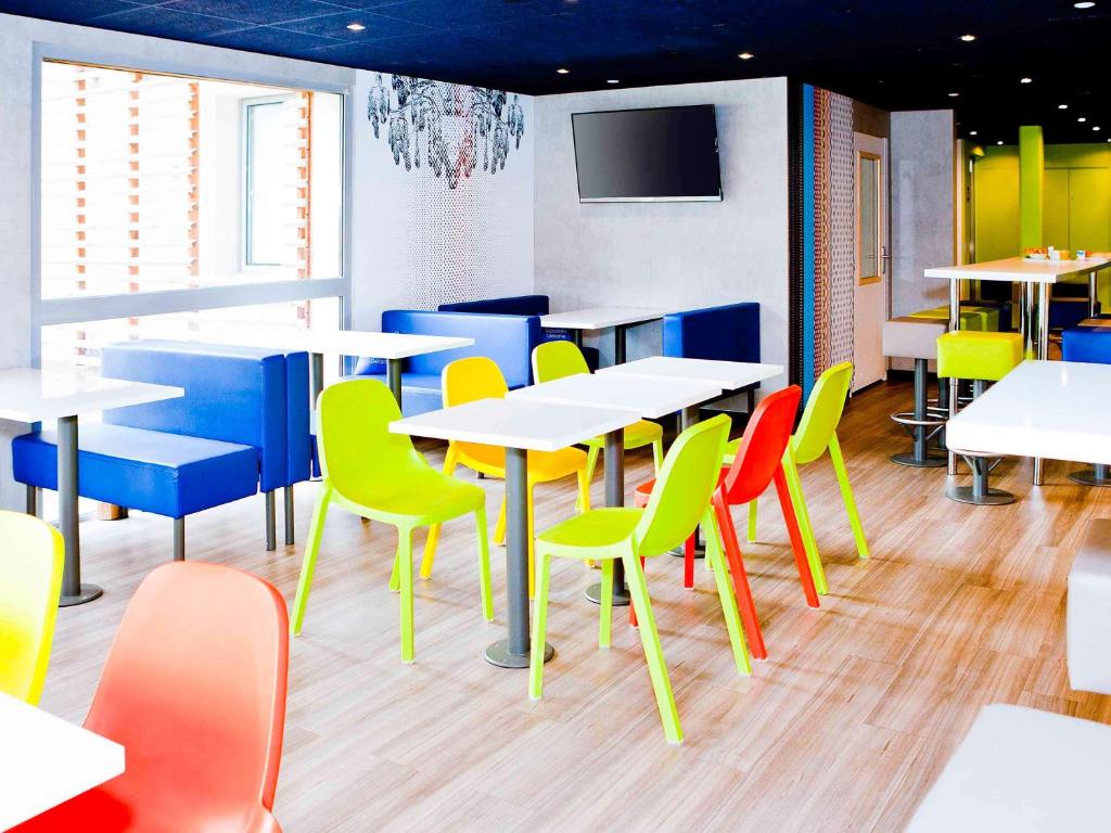 ibis budget Metz Technopole في ميتز: غرفة طعام مع طاولات وكراسي ملونة