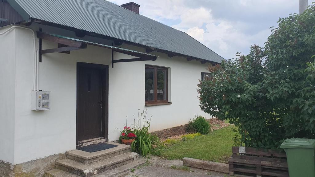 Biały dom z czarnymi drzwiami i ogródkiem w obiekcie Domek na wsi 