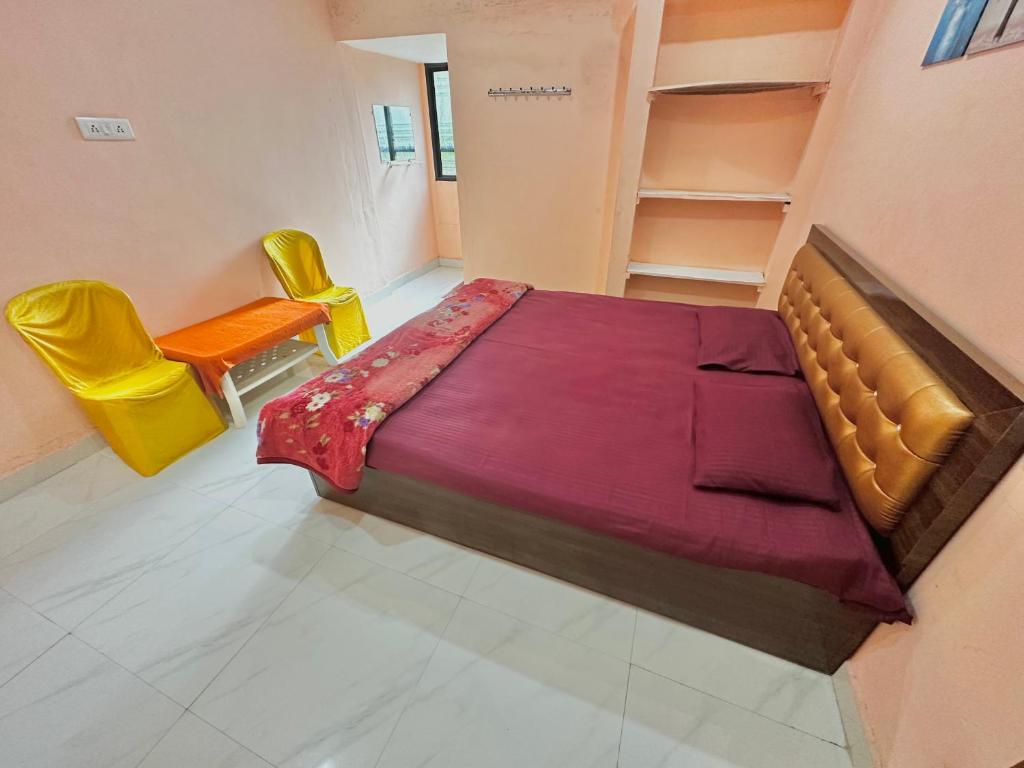 a bedroom with a bed and two yellow chairs at Hotel Tathastu in Rāmtek