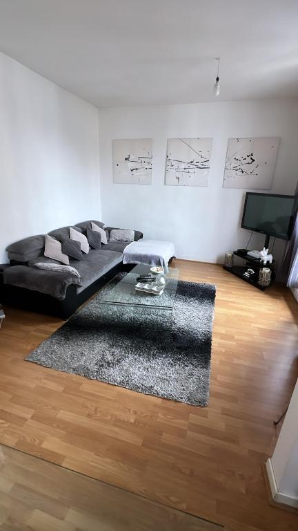 - un salon avec un canapé noir et un tapis dans l'établissement Appartement 60 m², porte de Saint-Cloud, à Boulogne-Billancourt