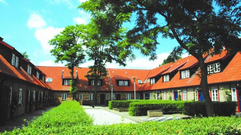 an orange roofed building with a pathway and trees at Österlens Golfklubb - Lilla Vik in Simrishamn