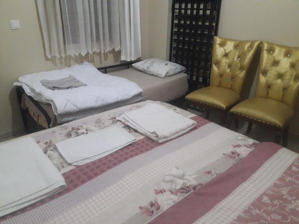 two beds and two chairs in a room at Yenifoça taş ev in Foça