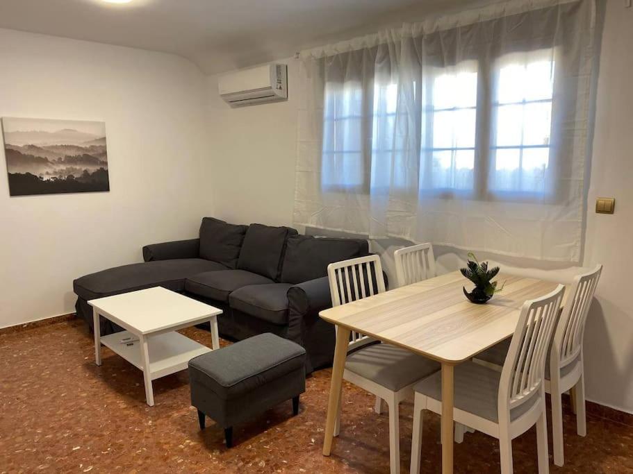 a living room with a couch and a table and chairs at Piso grande de 120 m2, a 15' de la playa en coche in Huelva