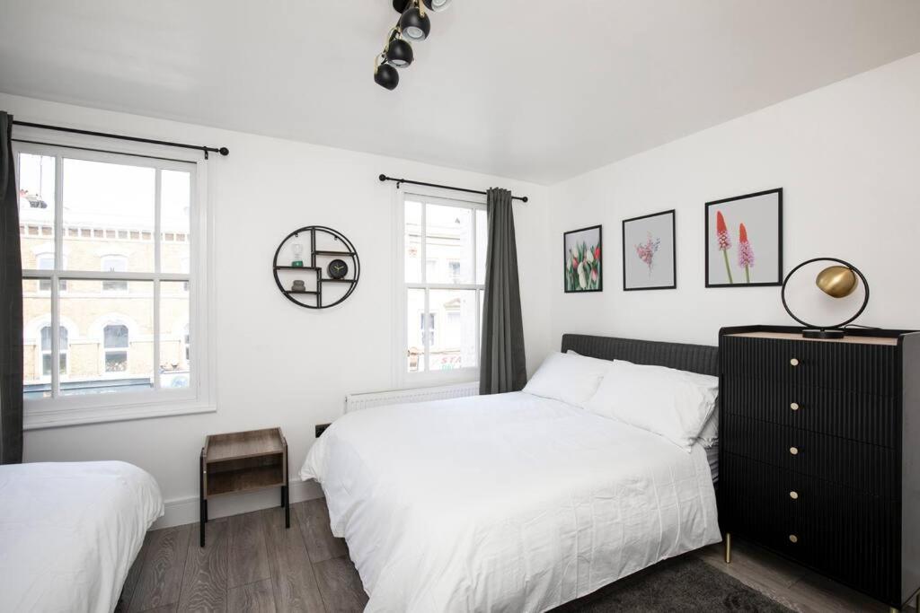 a white bedroom with two beds and a window at Spacious Serenity in the Heart of Central London in London