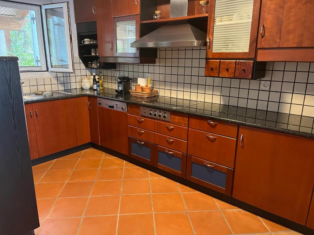 a kitchen with wooden cabinets and an orange floor at Villa House 200 with sea view in Spetses