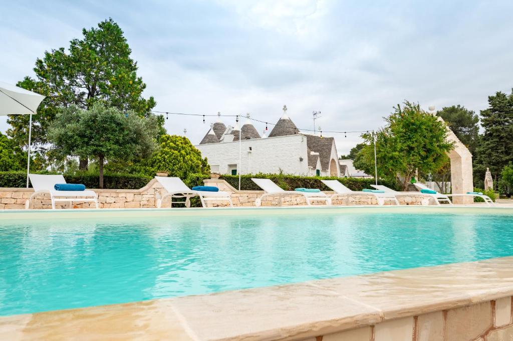 a swimming pool with chairs and a building at Trullo Suite in Masseria in Cisternino