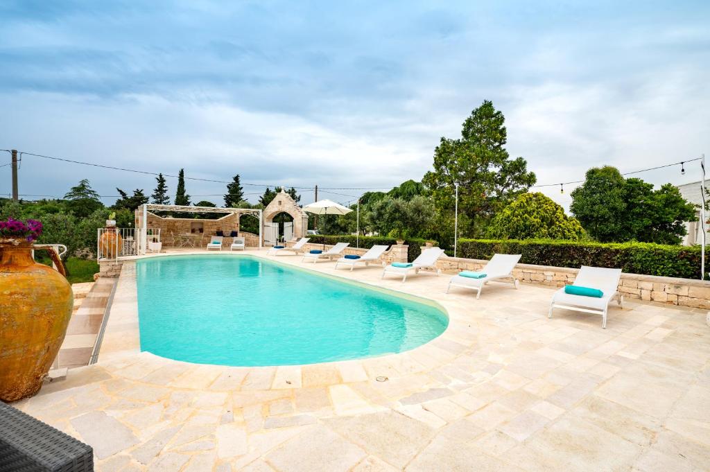 a swimming pool with lounge chairs and a vase at Trullo il Focolare in Masseria in Cisternino