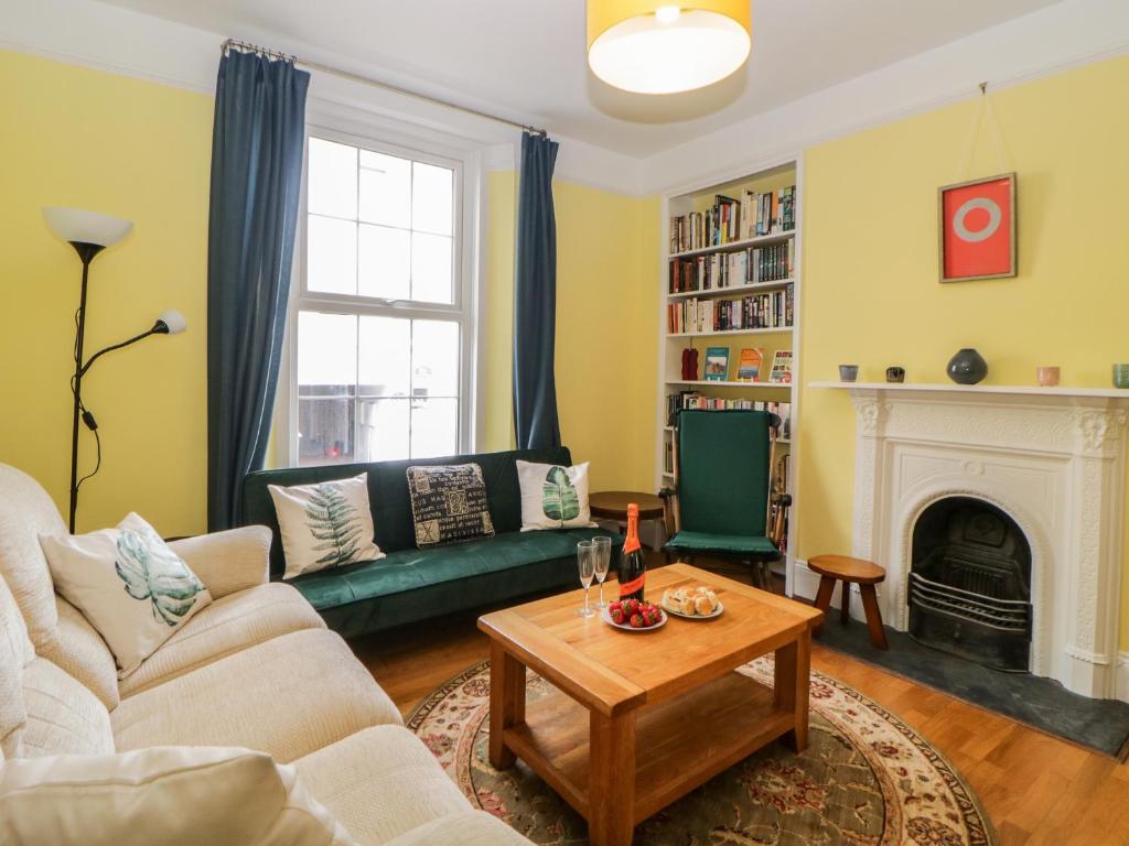 27 Exeter Street في تيغنماوث: غرفة معيشة مع أريكة خضراء ومدفأة
