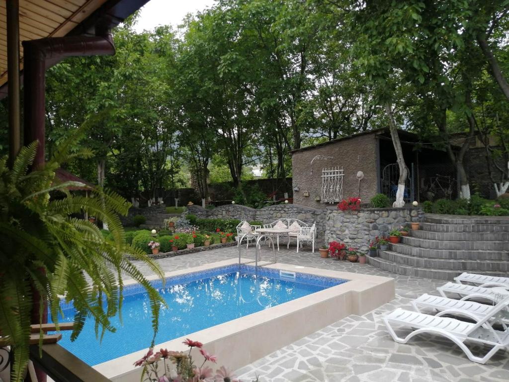 uma piscina com cadeiras brancas e uma mesa e escadas em Family Hotel Lago & Wine Cellar em Lagodekhi