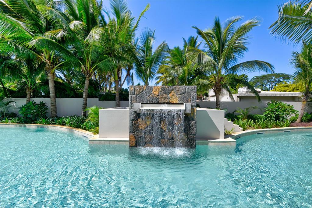 a water fountain in a pool with palm trees at Ki Residence in Grand Baie