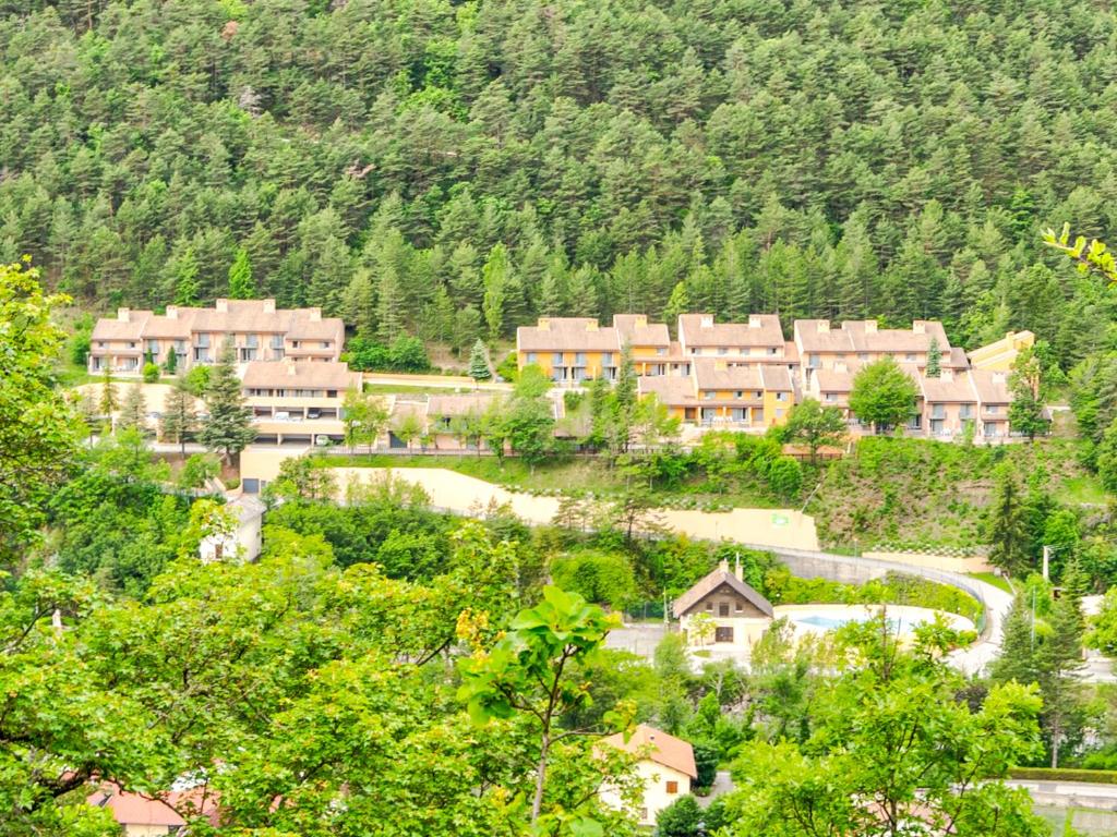 un grupo de edificios en una montaña con árboles en Vacancéole - Résidence Les Gorges Rouges, en Guillaumes