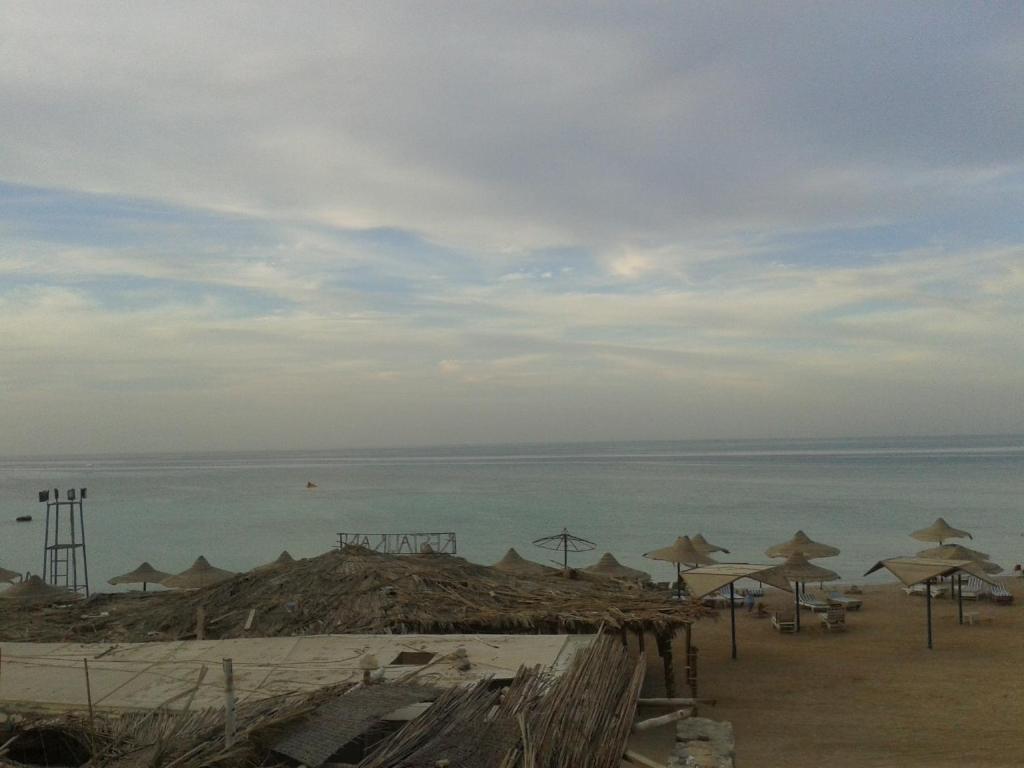 a beach with umbrellas and the ocean on a cloudy day at Al Dahar apartments Hurghada in Hurghada
