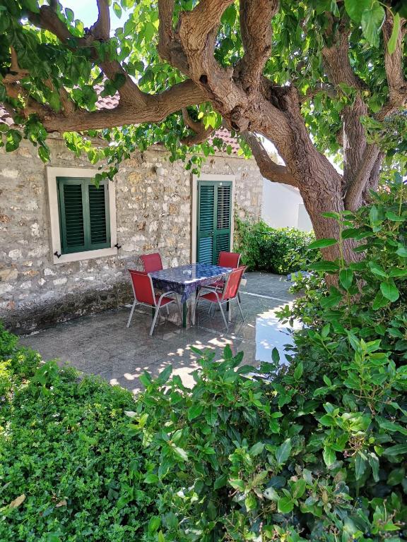 a table and chairs sitting under a tree at Apartments Kokotic in Bol