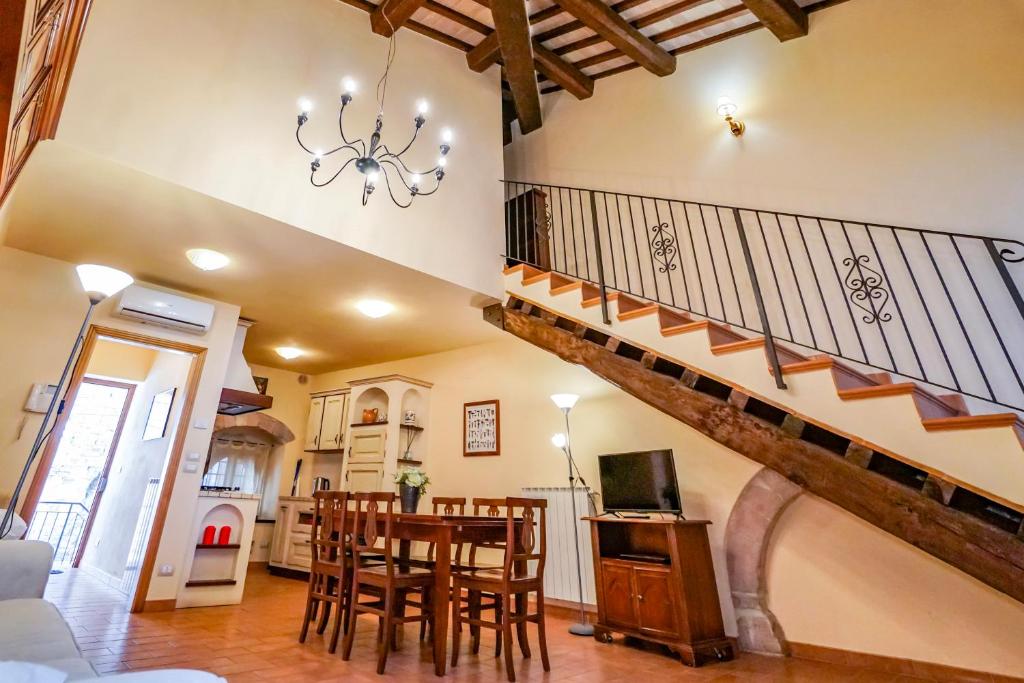 een woonkamer met een trap en een tafel en stoelen bij Maison Quintavalle 20 in Assisi