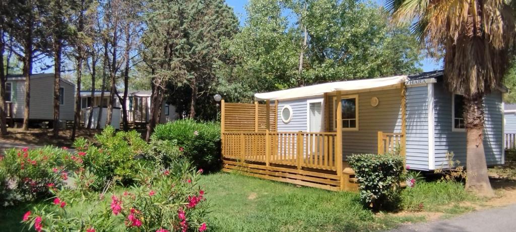a small cabin in a yard with flowers at Camping Parc des 7 Fonts in Agde