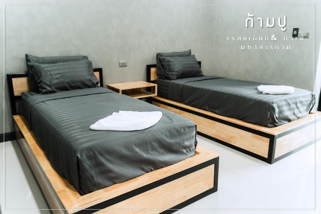 2 camas en una habitación con bases de madera en Khampu Resident ก้ามปู เรสซิเด้นท์, en Maha Sarakham
