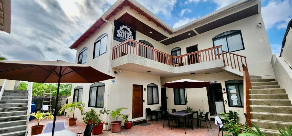 ein Haus mit einer Terrasse und einem Sonnenschirm in der Unterkunft Apartahotel Casa Soleil in Puerto Villamil