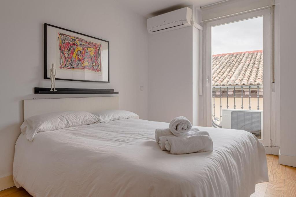Una cama blanca con una toalla y una ventana en Studio La Latina by SharingCo, en Madrid