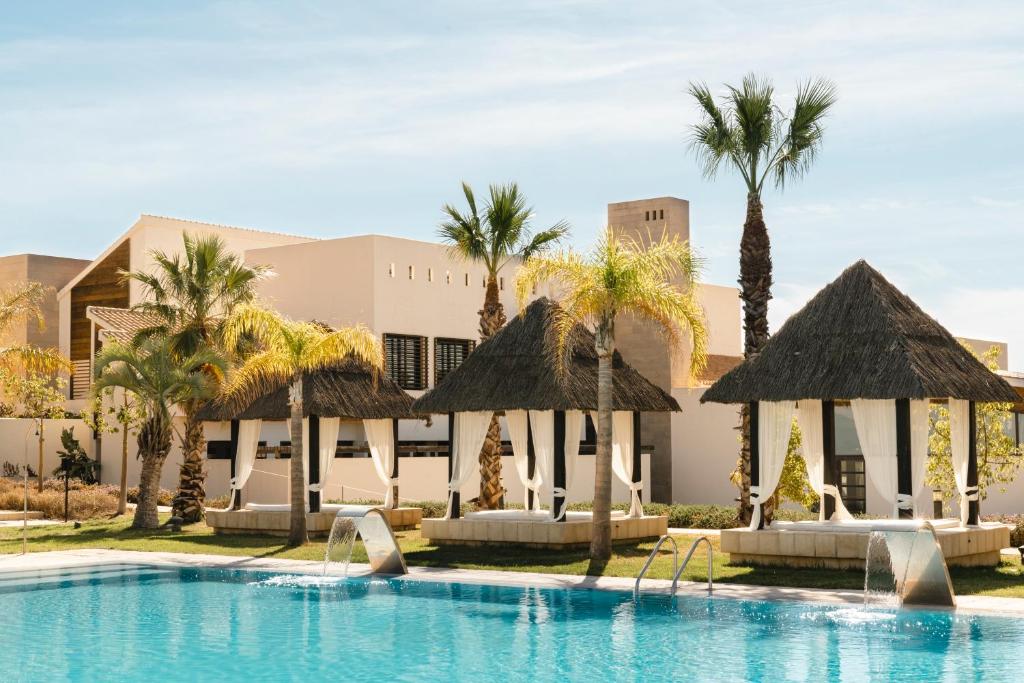 a pool at a resort with palm trees and umbrellas at Ona Hacienda del Álamo Golf Resort in Fuente Alamo