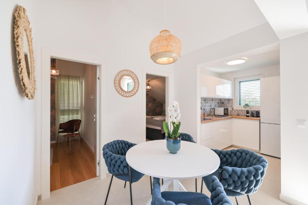 斯維斯托的住宿－Apartments Mila M，厨房以及带白色桌子和蓝色椅子的用餐室。