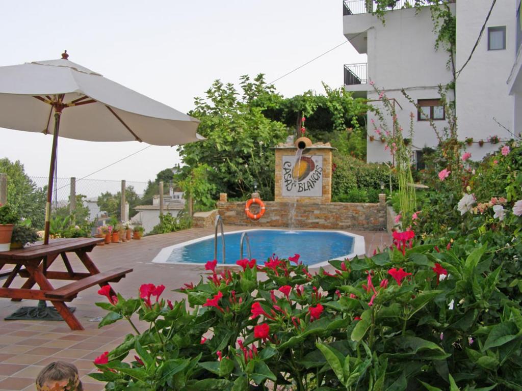 a swimming pool with a picnic table and flowers at CASASBLANCAS. Casa nr 6 in Mecina Bombarón