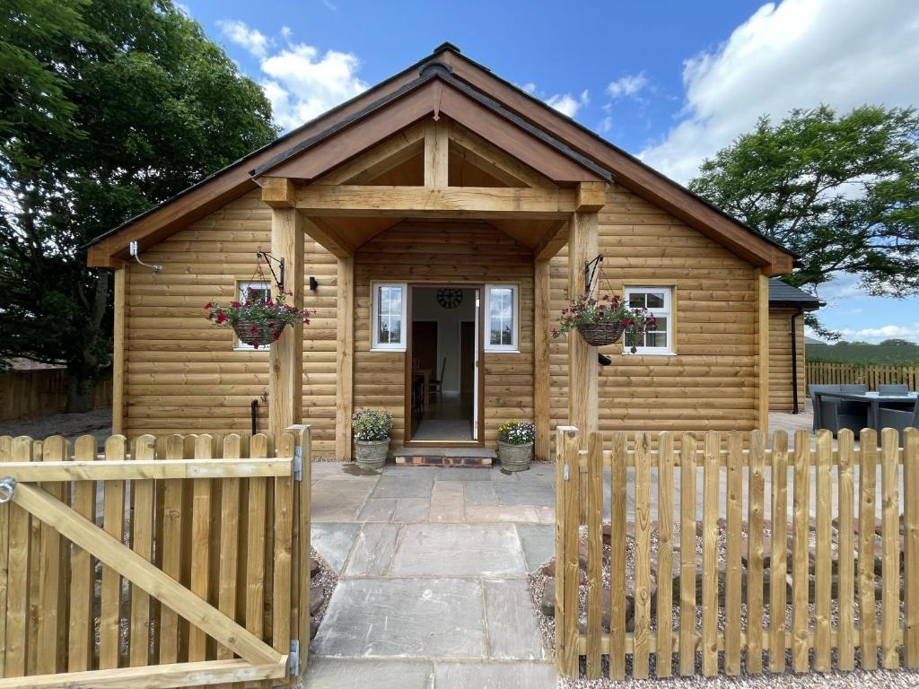 a wooden cabin with a fence in front of it at The Haystack Lodge in Tarporley