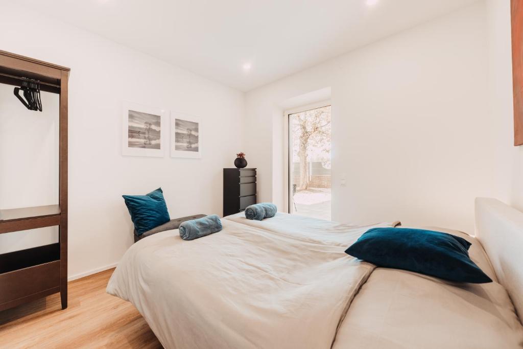 a white bedroom with a large bed with blue pillows at WOHNEN BAHNSTRASSE 5 in Klagenfurt
