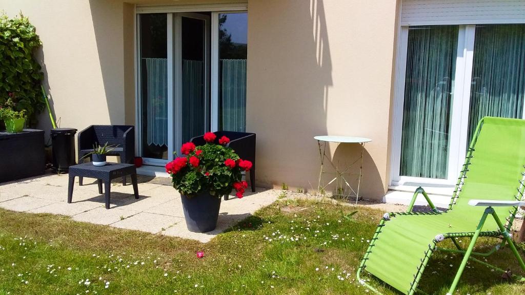 un portico con una sedia verde e un vaso di fiori di Appartement d'une chambre avec jardin clos et wifi a Carentan les Marais a Carentan
