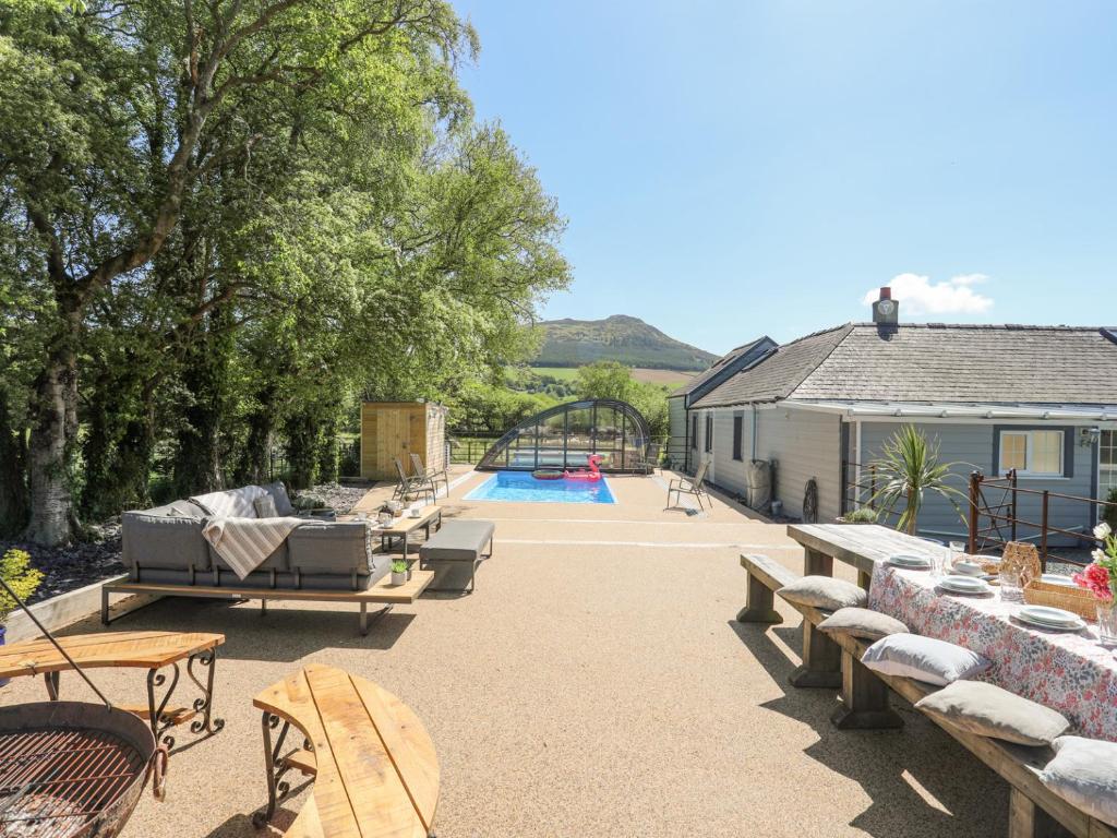 a patio with benches and a pool and a house at The Keepers Lodge in Pwllheli