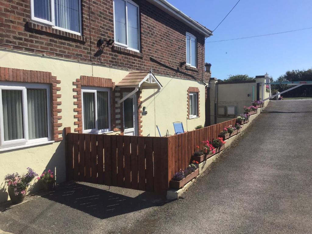 a house with a wooden fence and flowers on it at Frankies Flat, a Superb apartment in Flamborough. in Flamborough