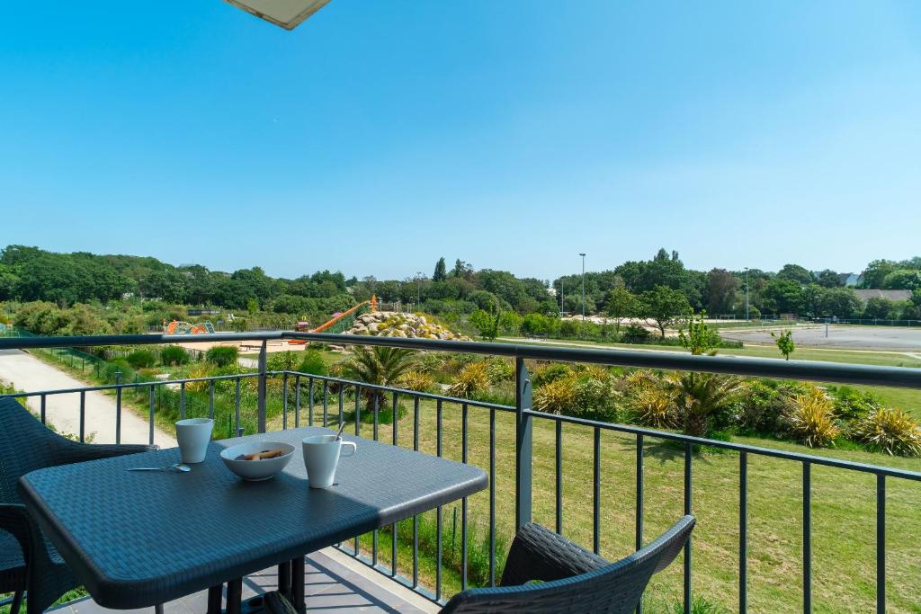 a table and chairs on a balcony with a view at Les Thermes 515 - Appt avec piscine partagée in Concarneau