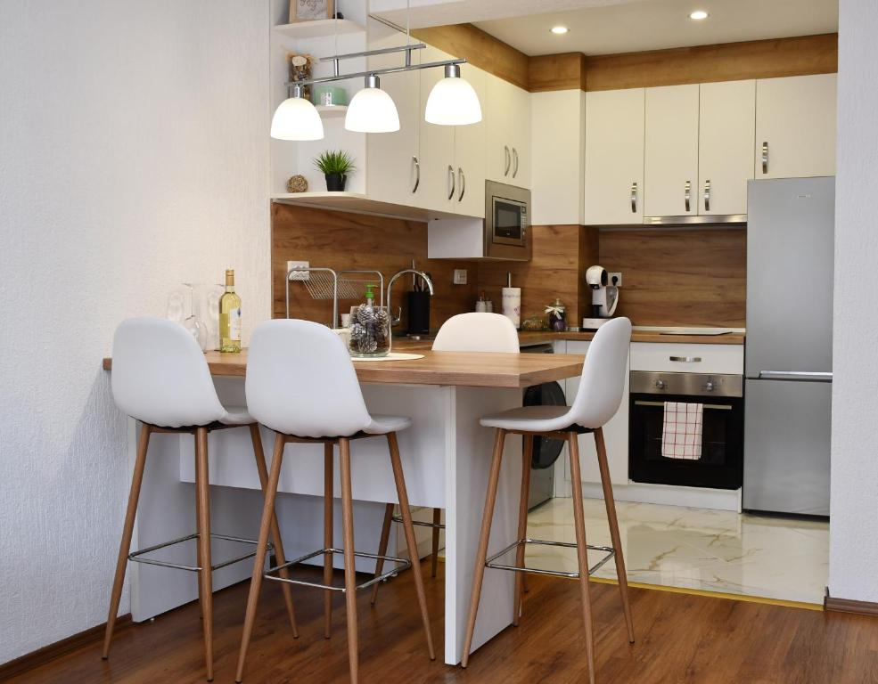 een keuken met witte stoelen en een houten aanrecht bij Comfort 37 - Luxury ski apartment near the gondola in Bansko