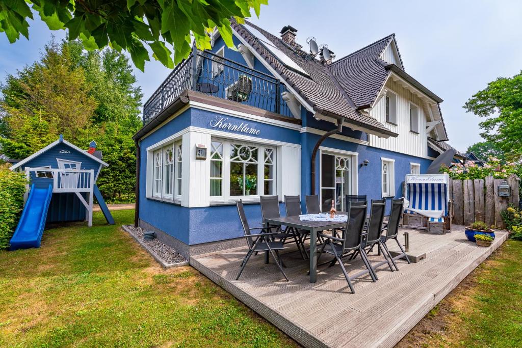 ein blaues Haus mit einem Tisch und Stühlen auf einer Terrasse in der Unterkunft Die Kornblume in Zingst