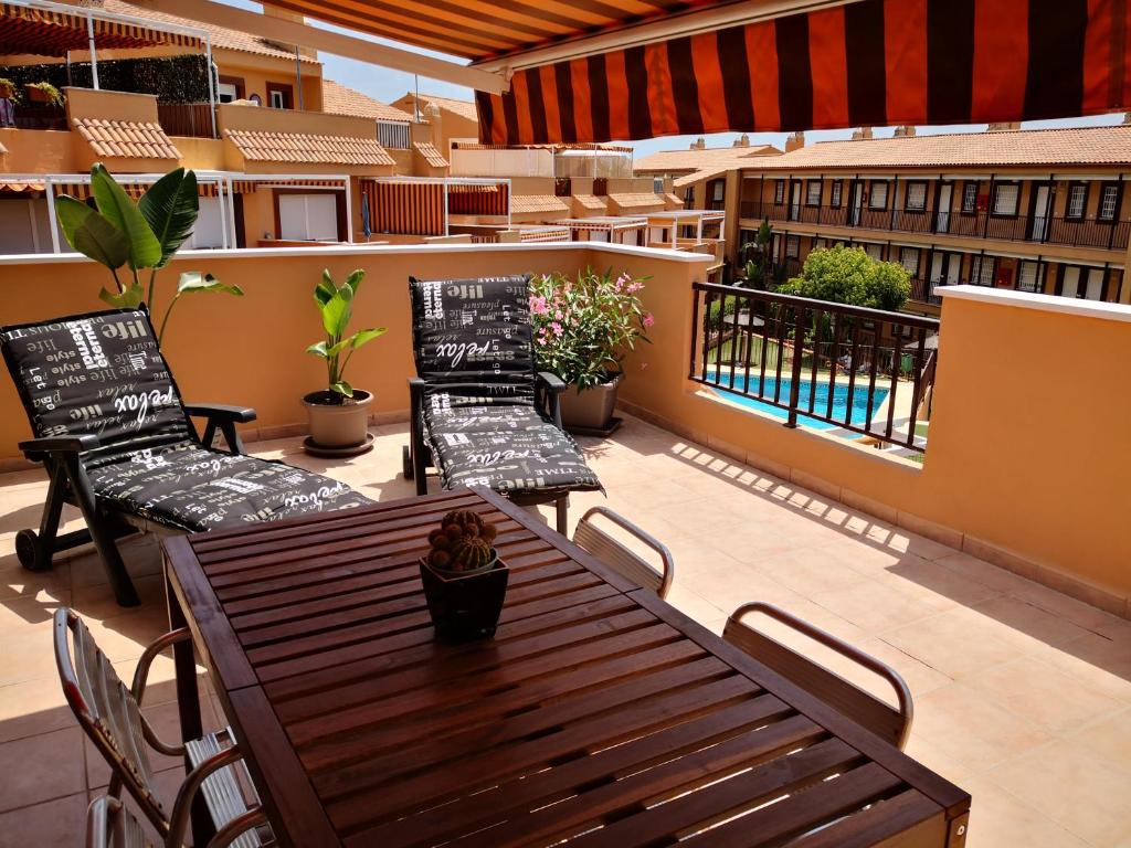 un patio con tavolo e sedie in legno sul balcone. di Marina de Casares Suites a San Luis de Sabinillas