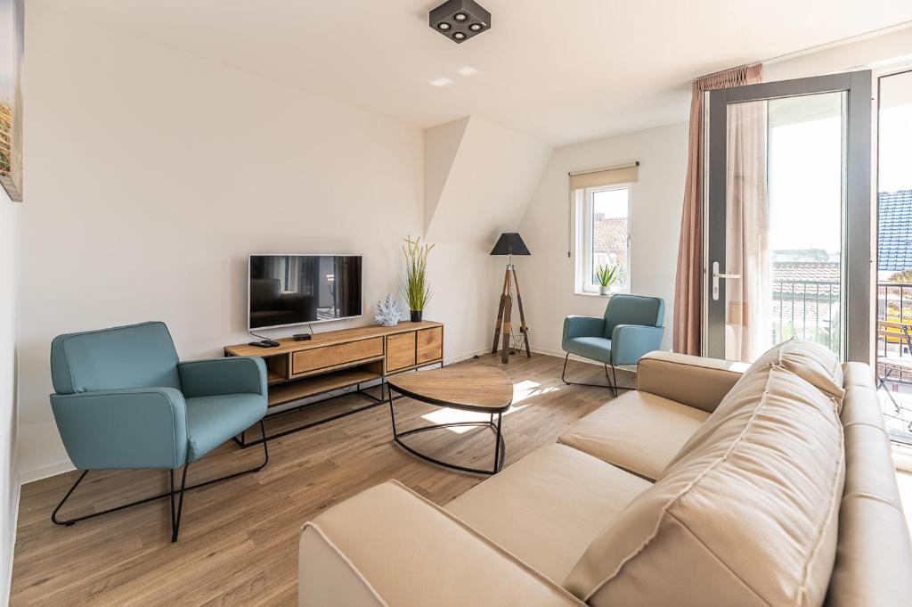 uma sala de estar com um sofá e duas cadeiras e uma televisão em Boutique Resort Schaardijk vakantieappartement em Scharendijke