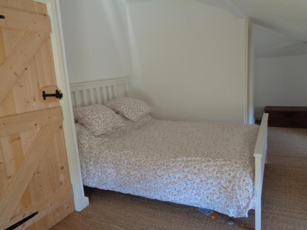 a small bedroom with a bed and a wooden door at The Mad Hatters Kitchen in Chaunay