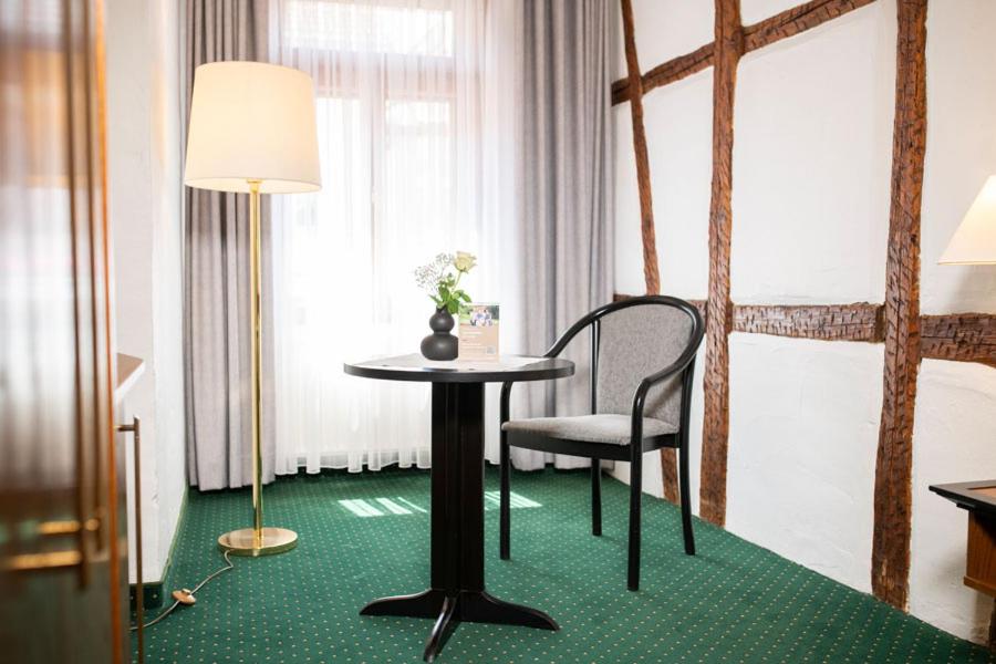 a room with a table and a chair and a lamp at Ringhotel Schlossberg in Neustadt