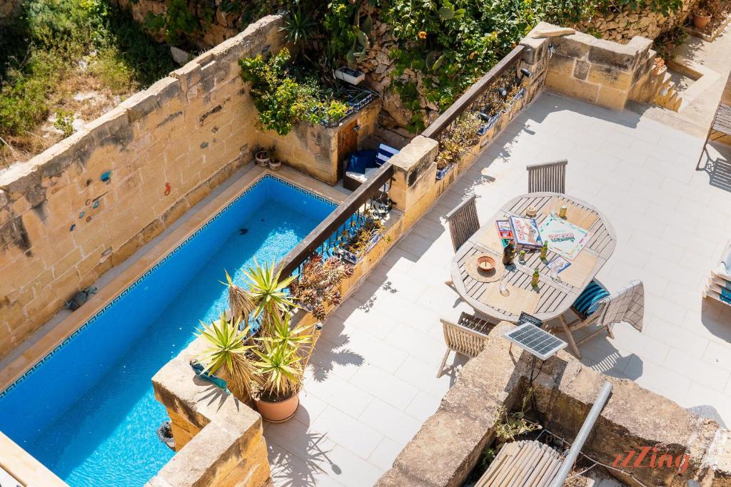 una vista aérea de una piscina con mesa y sillas en Matli Farmhouse, your stunning Gozo getaway., en Munxar