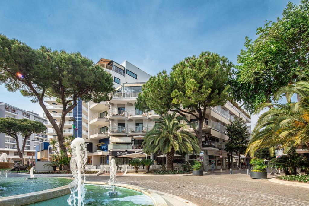 una fontana di fronte a un edificio alberato di Hotel Monaco a Lignano Sabbiadoro