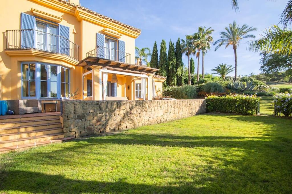 索托格蘭德的住宿－Sotogrande - El Jardin de Golf，一座黄色的房子,有石墙和院子