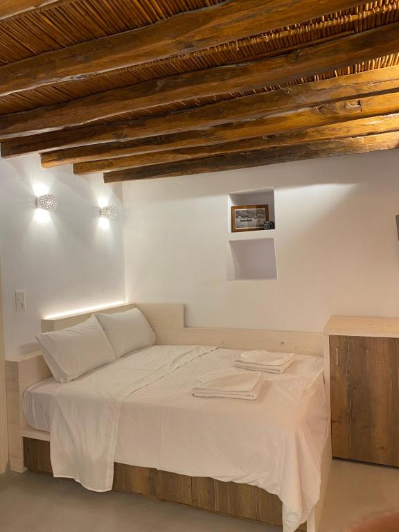 una camera da letto con letto, lenzuola bianche e soffitti in legno di Cozy apartment Kostos a Kóstos