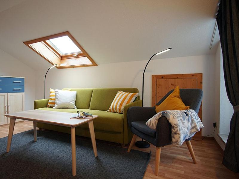 ein Wohnzimmer mit einem grünen Sofa und einem Tisch in der Unterkunft Gästehaus Math in Oberstdorf