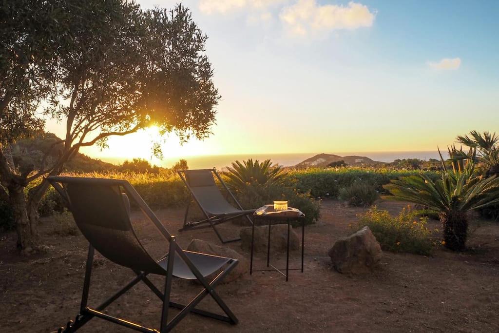 a couple of chairs and a table with the sunset at iFlat Dammusi Thienzo in Pantelleria