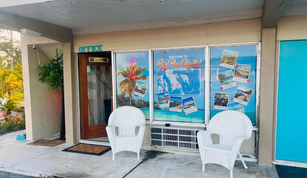 Deux chaises blanches assises à l'extérieur d'un bâtiment dans l'établissement Big Pine Key Motel, à Big Pine Key