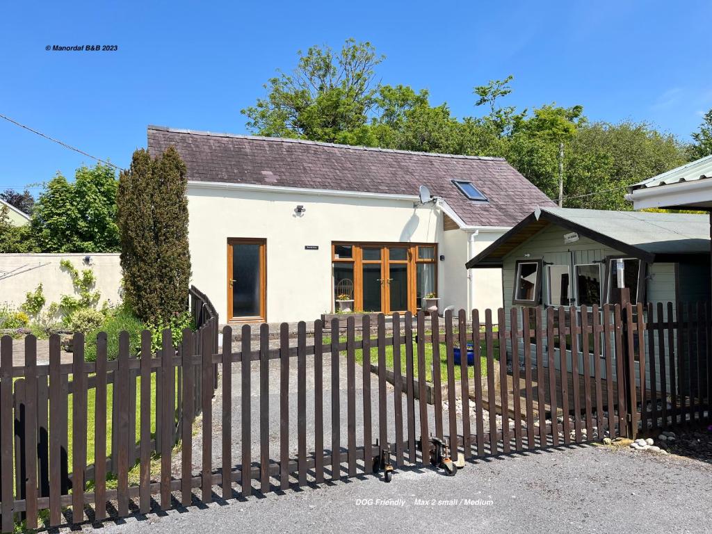 a wooden fence in front of a white house at Manordaf Holiday Cottage in St Clears