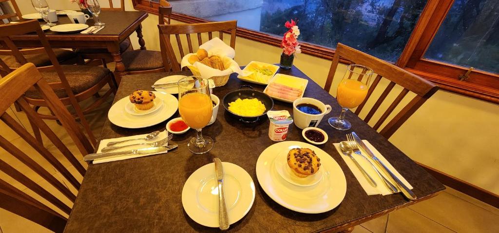 a table with plates of food and glasses of orange juice at Hotel y Cabañas Las Mellizas - Caja Los Andes in Los Ángeles