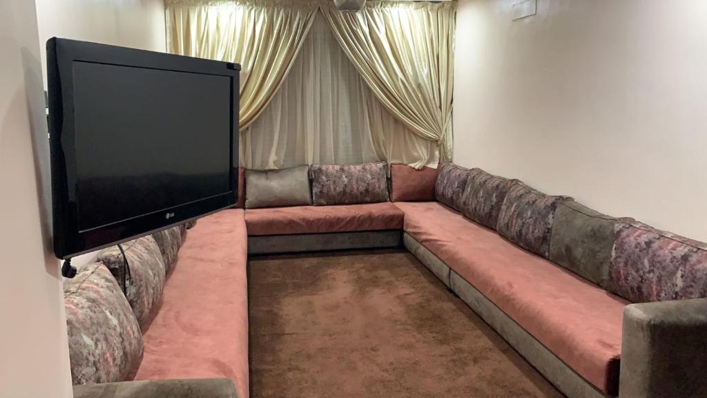 a living room with a large couch and a flat screen tv at TRIO in Agadir