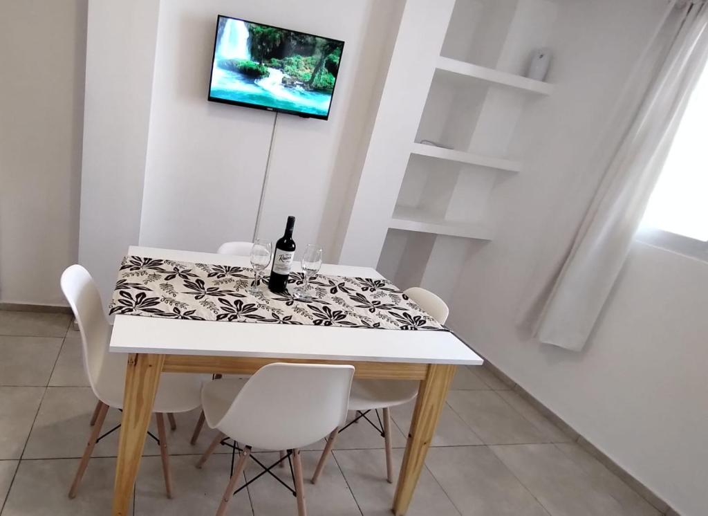 una mesa de comedor con sillas blancas y una botella de vino en Céntrico departamento en Godoy Cruz, Mendoza en Godoy Cruz